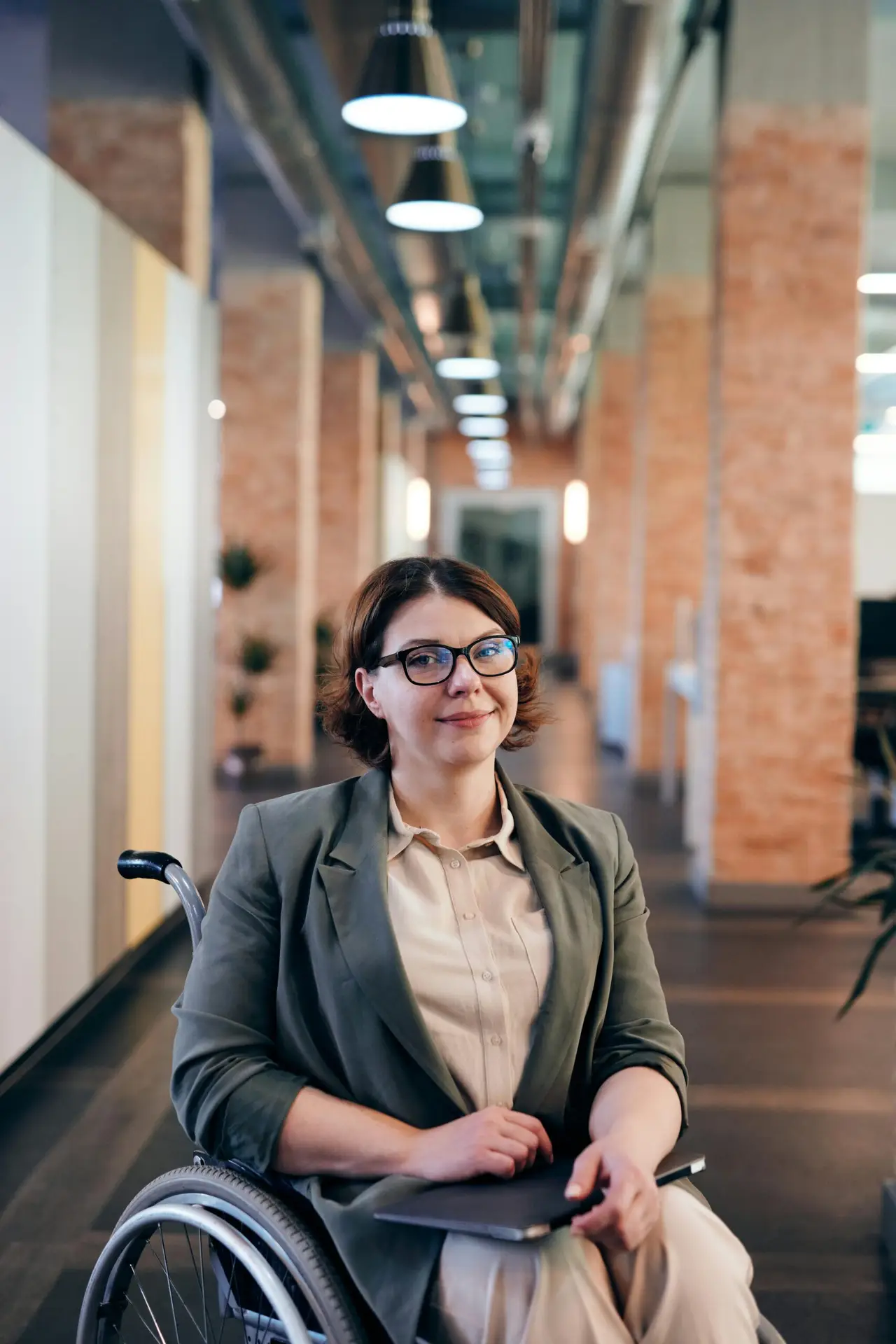 Professional businesswoman in a wheelchair smiling confidently in modern office.