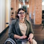 Professional businesswoman in a wheelchair smiling confidently in modern office.