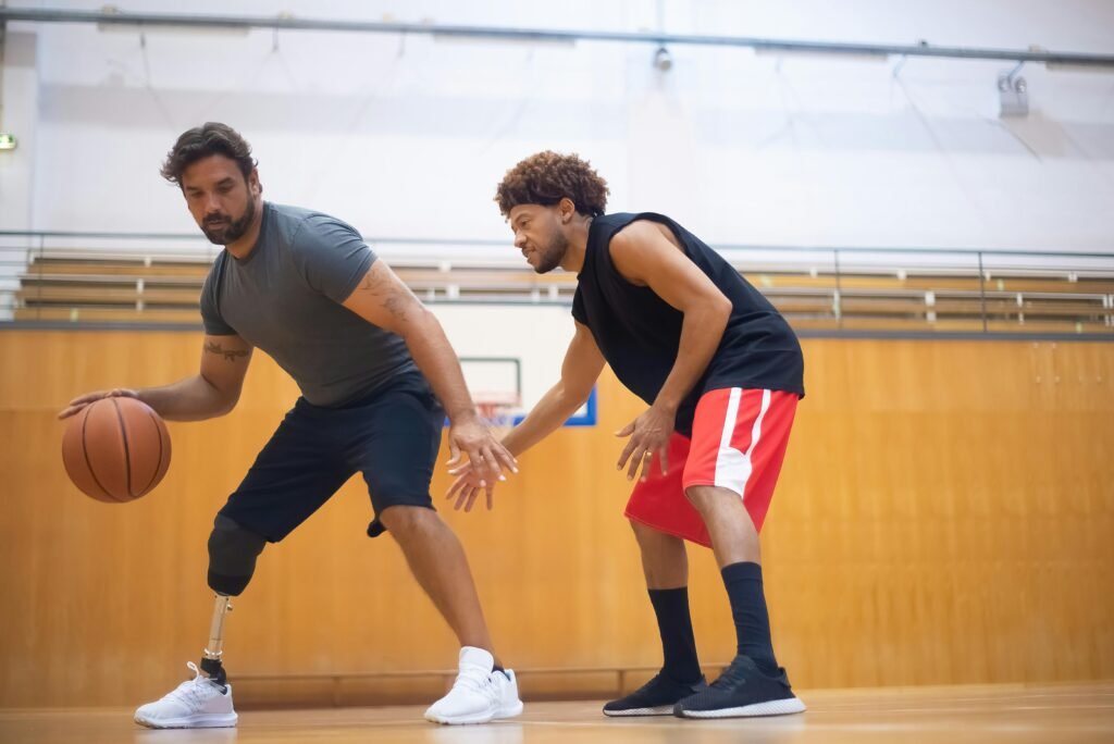 Two men playing basketball indoors, showcasing teamwork and inclusivity.